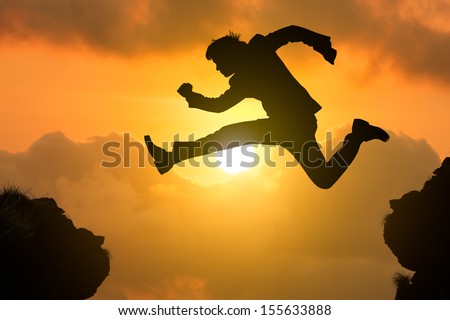 Silhouette businessman jump through the gap with sunset, Business competition concept