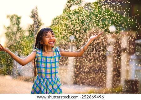 Happy little asian girl in the summer rain