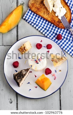 Variety of white cheese on a plate with fruits and bread