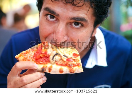 hungry man biting, eating slice of pizza