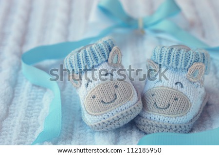 Knitted baby shoes for boy on a blue background. Greeting card.