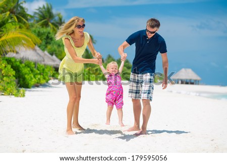 Happy family having fun on the white sandy beach on Maldives. Family of three having tropical vacation.