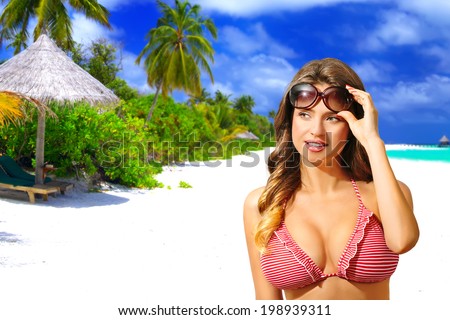 Beautiful sensual woman with bikini and sunglasses, on the white sandy beach, Maldives. Half body portrait, long curly blond hair