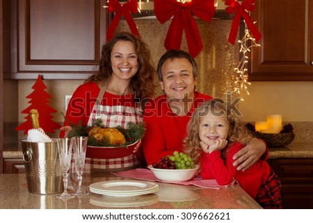 Happy family of three celebrating New Year, Christmas or Thanksgiving day with baked turkey or chicken