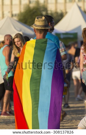 PRAGUE - AUGUST 15, 2015:  A man with a hat and a large rainbow flag at Letna park on the fifth Gay Prague Pride 2015