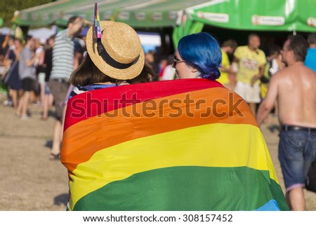 PRAGUE - AUGUST 15, 2015:  A couple wearing a large rainbow flag at Letna park on the fifth Gay Prague Pride 2015