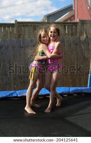 Children jumping on a trampoline in summer in there back yard