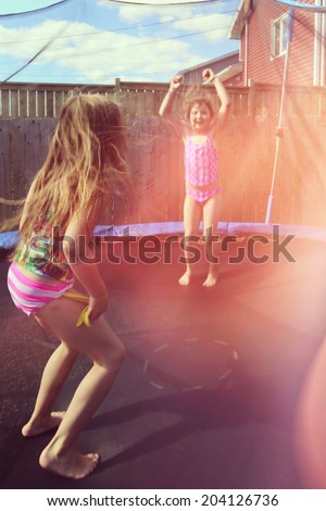 Children jumping on a trampoline in summer in there back yard