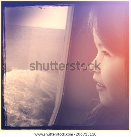 Adorable girl looking out window on boat - instagram effect