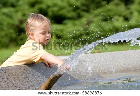 young boy playing in a public fountain