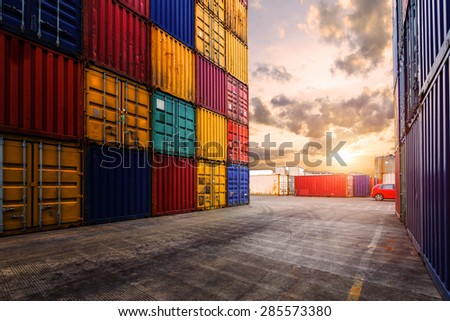 Empty road near stack of containers during sunset