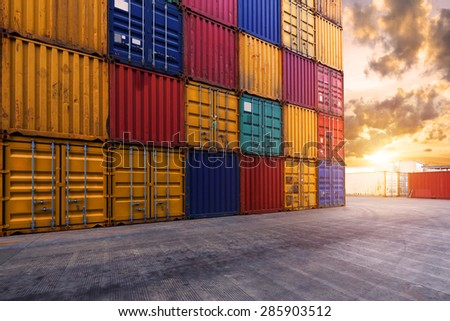 stack of containers with empty cement road in its front with sky during sunset.