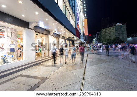 Modern shopping street and people in urban city with cement road at night