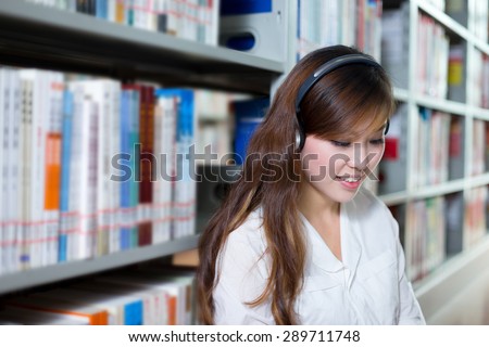Asian beautiful female student listen to music in library