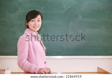 Pretty   young asian  teacher in front of a blackboard