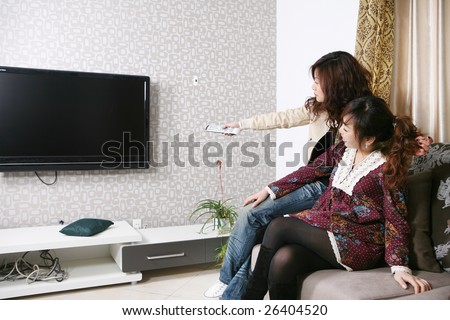 two women watch TV at home