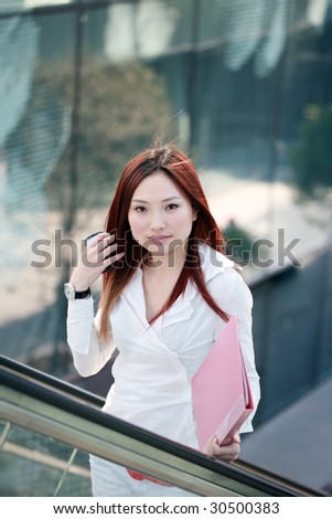 young asian businesswomen holding folder on escalator