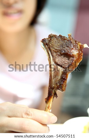 woman holding a Lamb shank in dining-hall