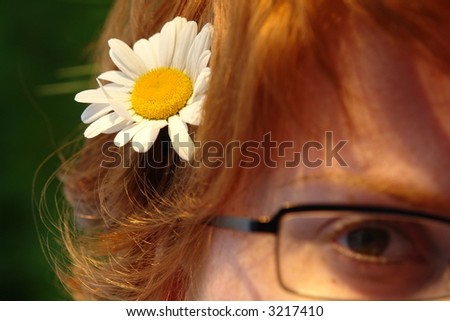 Beautiful summer woman lying in the grass with a daisy in her hair