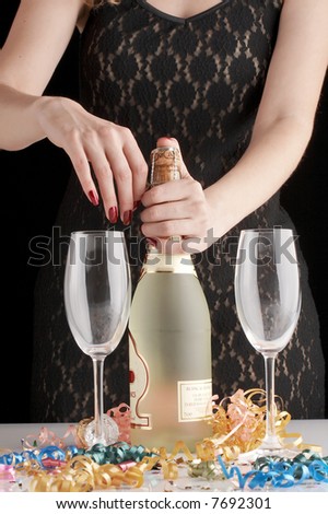 woman in sexy black evening dress opening bottle of Champagne