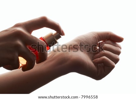 woman applying perfume on her wrist, small bright red perfume bottle