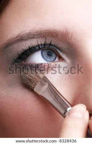 makeup artist applying blue eye powder with brush, girl with blue eye