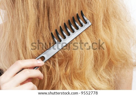 woman combing her hair with black special comb, beauty salon