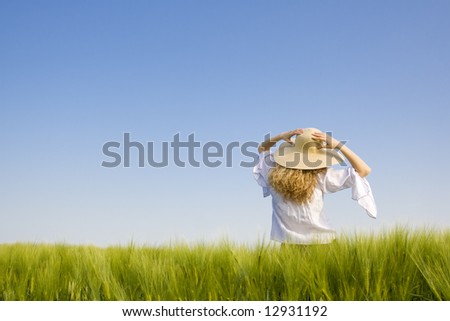 happy girl with big hat in a green wheat  field against blue sky