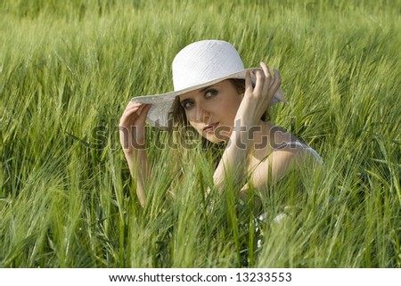 \'happy in nature\' ;blond girl with white hat in a wheat field