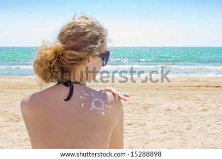 sun protection; woman on the beach putting on lotion