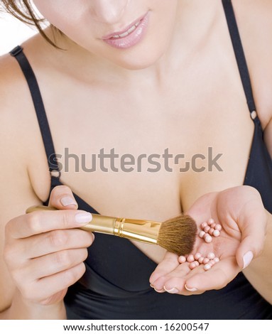 woman holding bronzing pearls and thick golden brush