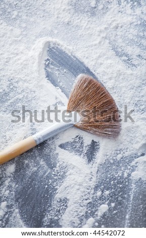 thick professional fan brush and loose white powder particles scattered around