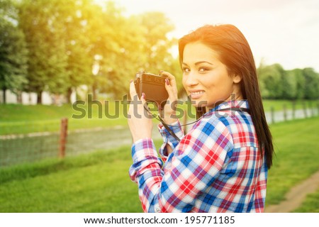 Young hipster female photographer in nature. Mixed raced young woman with old film camera photographing nature on her vacation. Photography, travel and modern lifestyle concept.