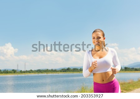 Young fit Caucasian sporty woman running outside by the sea in summer. Cute blonde woman jogging at the beach smiling. Natural light, healthy lifestyle, diet concept. Horizontal image.