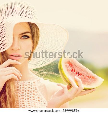 Beautiful young Caucasian blonde woman in beige crochet hat and top posing holding a slice of watermelon. Retouched, filter applied, square format.