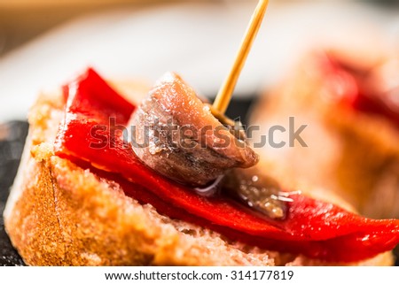 Red peppers with great anchovies on a slice of bread. Typical spanish food. Detail.