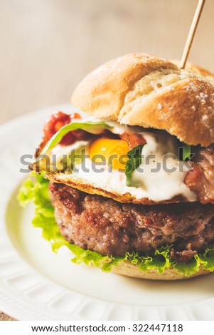 Great beef burger with fried egg, bacon, arugula and caesar sauce. Vintage color edition.