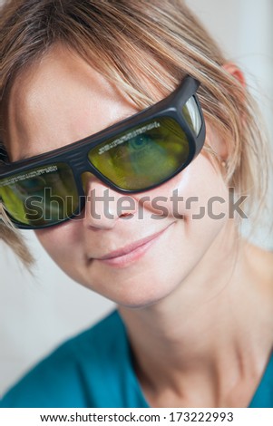 Smiling therapist or practitioner at a skincare clinic in protective goggles to protect her eyes against the laser therapy