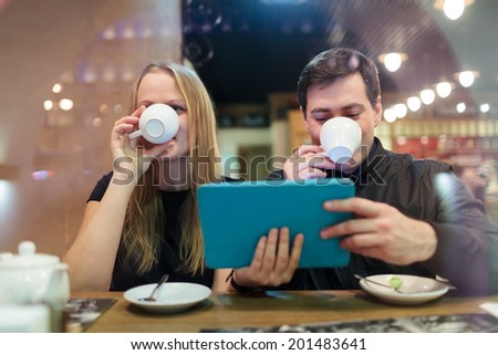 Man and woman drinking coffee while holding a smart tablet