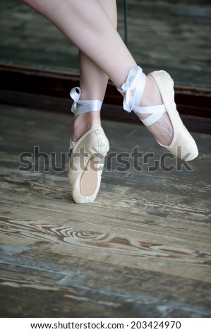 Close-up shot of female feet in ballet shoes dancing on the wooden floor