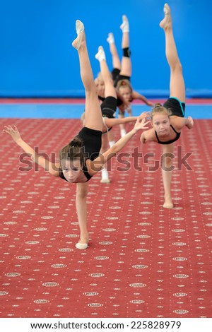 Group of girls exercising during gymnastic classes in the gym. They doing vertical leg-split