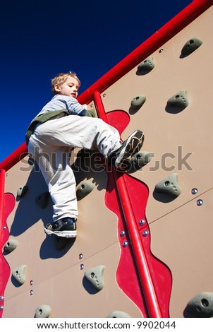 active boy scales a climbing wall