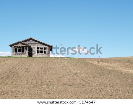 An abandoned house in a dirt field. Room for copy space