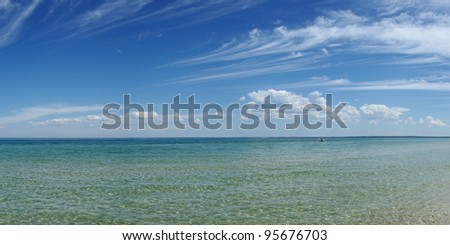 Reflections in clean water on sunny day with scenery clods on blue sky and empty boat at Port Philip Bay, Melbourne, Victoria, Australia