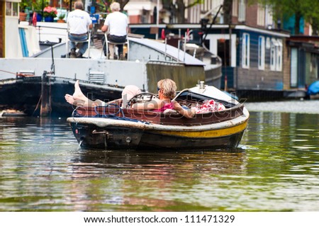 AMSTERDAM, JUNE 10: Motorboat with resting man on Amsterdam canal on June 10, 2011. Amsterdam has been called \