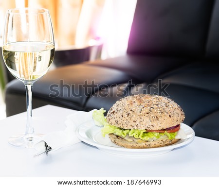 Burger and glass of white wine on table at restaurant