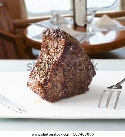 Closeup of roast meat ready to be carved with restaurant table on background
