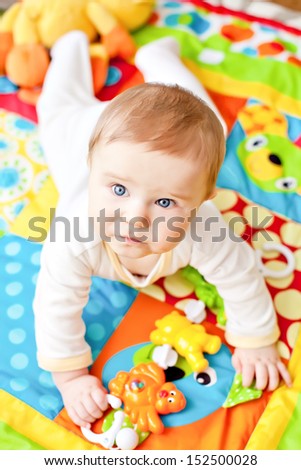 Closeup of happy six months baby boy crawling on colorful playmat