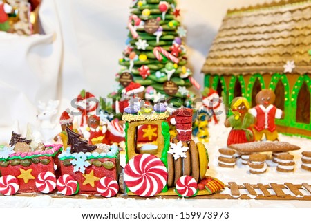 Happy gingerbread people gathered by the christmas tree looking at train as Christmas fun decoration