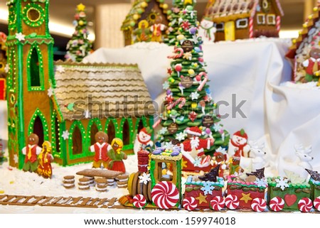 Happy gingerbread people gathered by the christmas tree and church looking at train as Christmas fun decoration